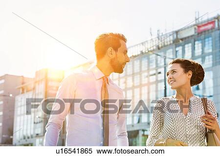 Stock Photography - Businessman and businesswoman walking while discussing plans before meeting. Fotosearch