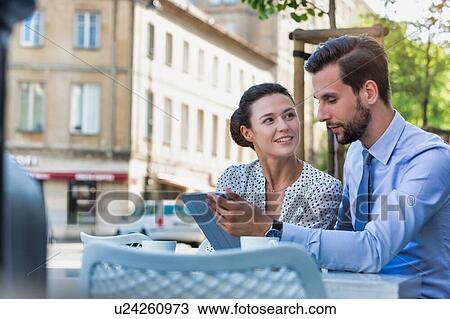 Businessman discussing plans over digital tablet to businesswoman while sitting and waiting for their food at restaurant View Large Photo Image Stock Image - Businessman discussing plans over digital tablet to businesswoman while sitting and waiting for their food at restaurant. Fotosearch