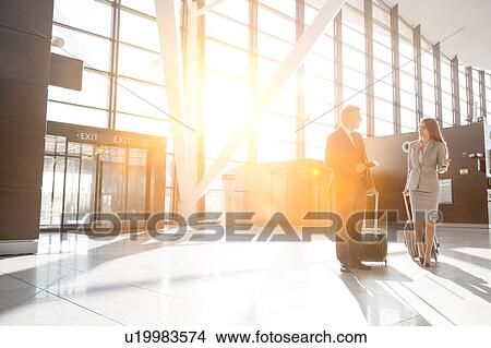 Picture - Businessman discussing plans with businesswoman in airport . Fotosearch