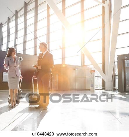 Stock Image - Businessman discussing plans with businesswoman in airport . Fotosearch