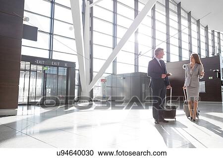 Businessman discussing plans with businesswoman in airport View Large Photo Image Stock Image - Businessman discussing plans with businesswoman in airport . Fotosearch