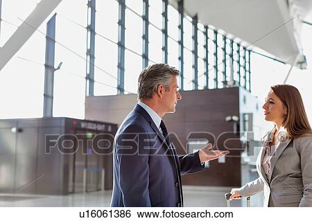 Stock Photograph - Businessman discussing plans with business partner in airport. Fotosearch