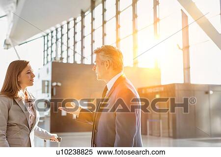 Stock Photography - Businessman discussing plans with business partner in airport. Fotosearch
