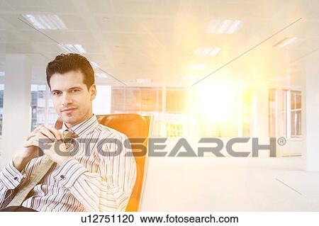 Stock Image - Businessman relaxing in chair in empty office. Fotosearch