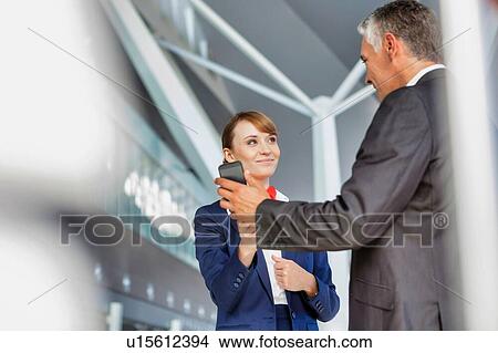 Businessman showing his electronic ticket on smartphone to passenger service agent in airport View Large Photo Image Picture - Businessman showing his electronic ticket on smartphone to passenger service agent in airport. Fotosearch
