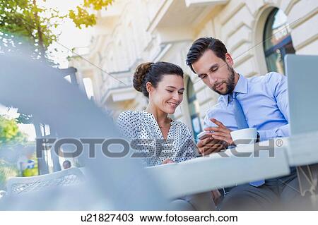 Businessman showing smartphone to businesswoman while having coffee during office break View Large Photo Image Stock Image - Businessman showing smartphone to businesswoman while having coffee during office break. Fotosearch
