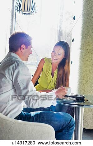 Stock Image - Businessman sitting while discussing plans with business partner in coffee shop. Fotosearch
