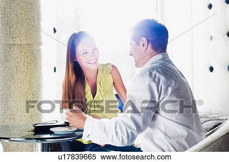 Stock Photography - Businessman sitting while discussing plans with business partner in lobby. Fotosearch