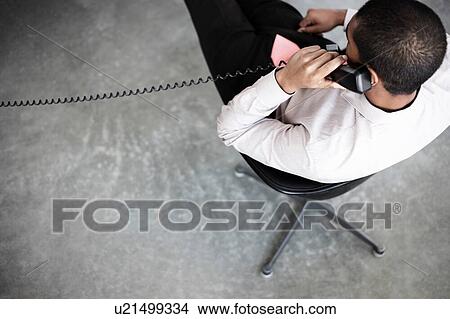 Picture - Businessman using corded phone from home during social distancing. Fotosearch