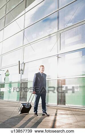 Businessman walking with his suitcase in the airport View Large Photo Image Stock Photo - Businessman walking with his suitcase in the airport. Fotosearch
