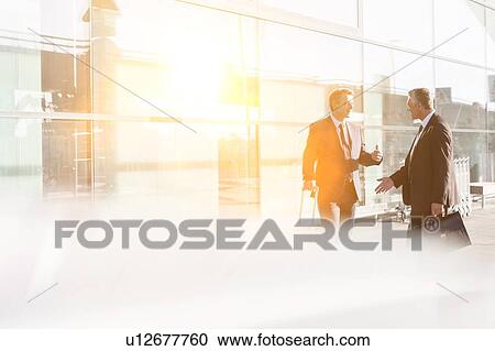 Stock Image - Businessmen discussing plans in the airport. Fotosearch