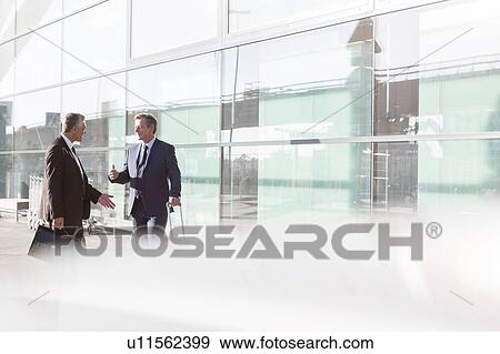 Stock Photo - Businessmen discussing plans in the airport. Fotosearch