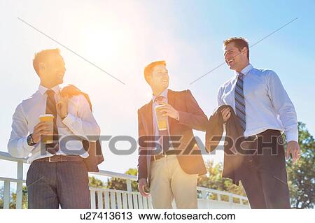Stock Image - Businessmen drinking coffee while walking and talking during break . Fotosearch