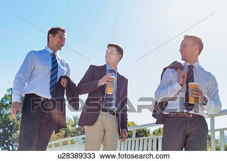 Stock Image - Businessmen drinking coffee while walking and talking during break . Fotosearch