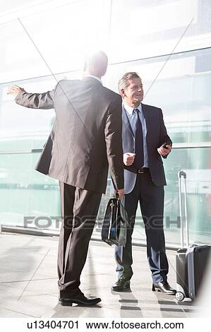 Businessmen talking while waiting for taxi in the airport View Large Photo Image Stock Image - Businessmen talking while waiting for taxi in the airport. Fotosearch