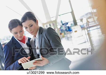 Stock Photo - Businesswoman asking for assistance with passenger service agent in airport. Fotosearch