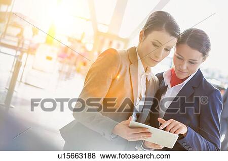 Stock Photo - Businesswoman asking for assistance with passenger service agent in airport. Fotosearch