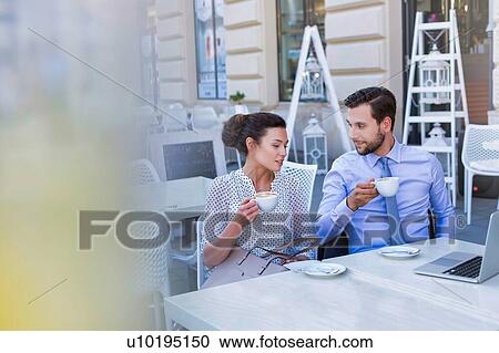 Stock Image - Businesswoman discussing plans with businessman while having coffee during office break. Fotosearch