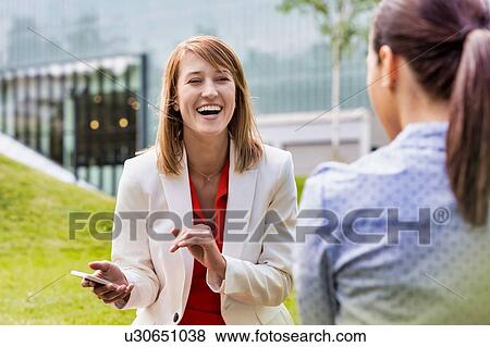 Businesswoman laughing while talking to her colleague View Large Photo Image Stock Photo - Businesswoman laughing while talking to her colleague. Fotosearch