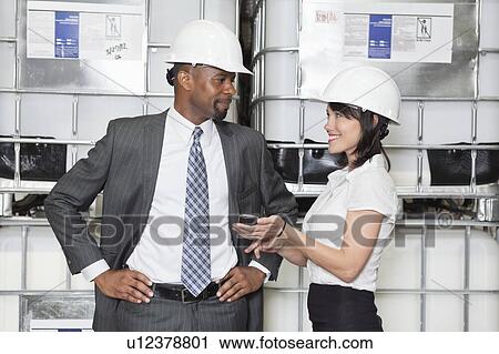 Businesswoman showing cell phone to male colleague View Large Photo Image Stock Image - Businesswoman showing cell phone to male colleague. Fotosearch