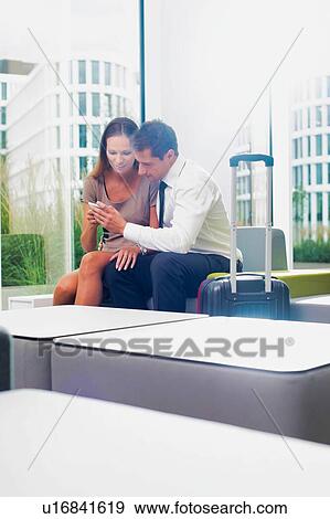 Businesswoman showing smartphone with businessman in hotel lobby View Large Photo Image Stock Photo - Businesswoman showing smartphone with businessman in hotel lobby . Fotosearch