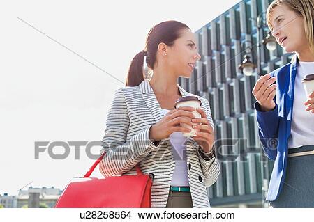 Businesswomen walking while talking outside office building View Large Photo Image Picture - Businesswomen walking while talking outside office building. Fotosearch