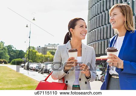 Businesswomen walking while talking outside office building View Large Photo Image Stock Image - Businesswomen walking while talking outside office building. Fotosearch