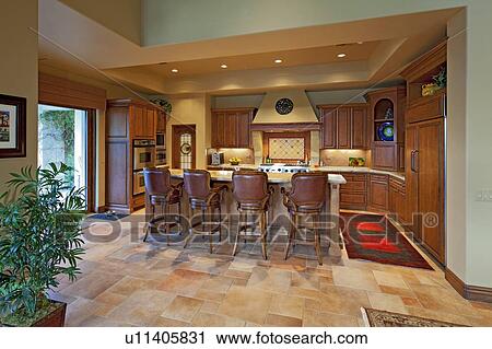 Stock Image - Chairs near contemporary kitchen counter in luxury manor house. Fotosearch