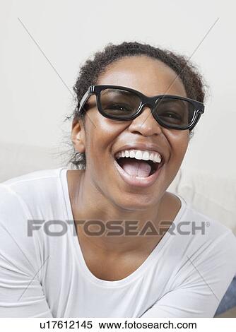 Cheerful young African American woman wearing 3D glasses and watching TV View Large Photo Image Stock Photography - Cheerful young African American woman wearing 3D glasses and watching TV. Fotosearch