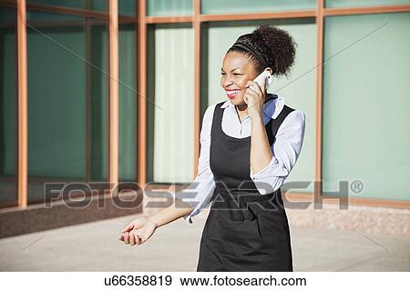 Stock Photo - Cheerful young woman in formals using mobile phone. Fotosearch