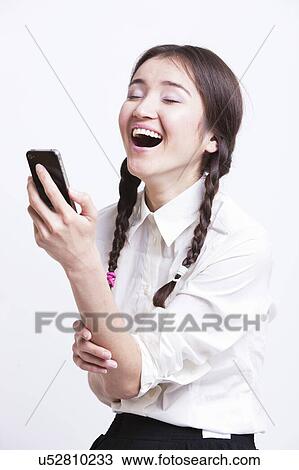 Stock Image - Cheerful young woman using cell phone against white background. Fotosearch