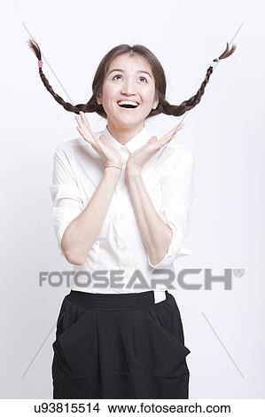 Cheerful young woman with braids curling upwards against white background View Large Photo Image Picture - Cheerful young woman with braids curling upwards against white background. Fotosearch