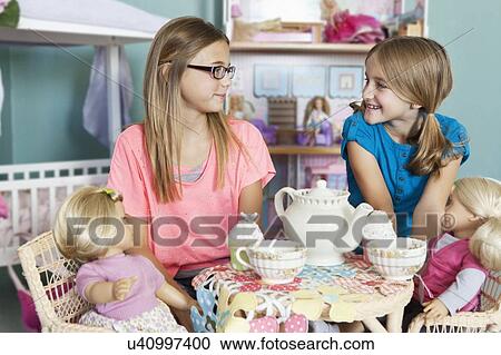 Stock Image - Children and dolls having tea party. Fotosearch