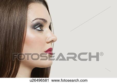 Stock Image - Close-up of a beautiful young woman over gray background. Fotosearch