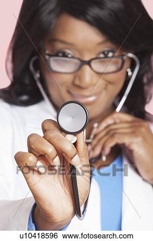 Close-up of female doctor holding stethoscope over pink background View Large Photo Image Stock Photograph - Close-up of female doctor holding stethoscope over pink background. Fotosearch