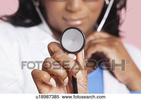 Close-up of female doctor holding stethoscope over pink background View Large Photo Image Stock Photography - Close-up of female doctor holding stethoscope over pink background. Fotosearch
