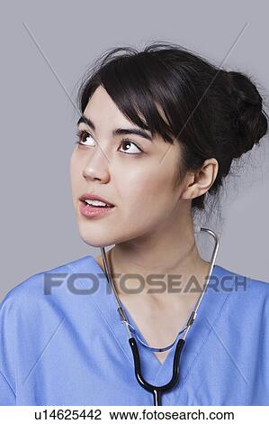 Close-up of mixed race female surgeon looking up over gray background View Large Photo Image Stock Image - Close-up of mixed race female surgeon looking up over gray background. Fotosearch