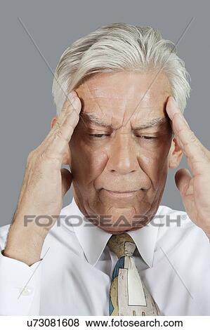 Stock Photo - Close-up of senior businessman with headache over gray background. Fotosearch