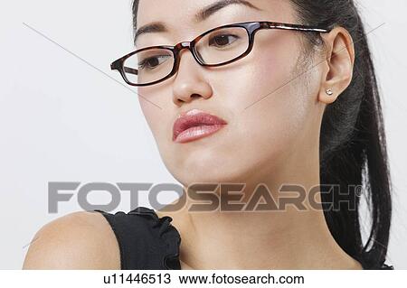 Stock Image - Close-up of young Chinese woman wearing glasses over white background. Fotosearch
