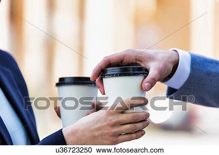 Close up photo of businesswoman giving businessman a cup of coffee View Large Photo Image Stock Image - Close up photo of businesswoman giving businessman a cup of coffee. Fotosearch