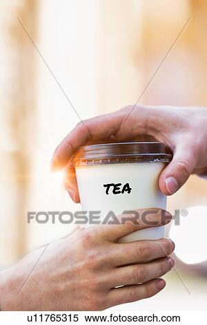 Stock Photography - Close up photo of businesswoman giving businessman a cup of tea. Fotosearch