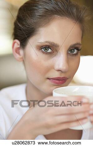 Close-up portrait of a young woman holding coffee cup View Large Photo Image Stock Image - Close-up portrait of a young woman holding coffee cup. Fotosearch