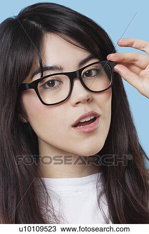 Close-up portrait of mixed race young woman wearing eyeglasses over blue background View Large Photo Image Stock Image - Close-up portrait of mixed race young woman wearing eyeglasses over blue background. Fotosearch