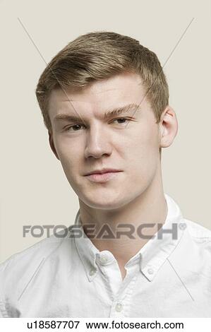 Stock Photo - Close-up portrait of serious young man against gray background. Fotosearch