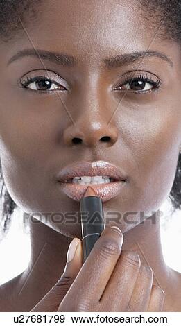 Close-up portrait of young African American woman applying lipstick View Large Photo Image Stock Photo - Close-up portrait of young African American woman applying lipstick. Fotosearch