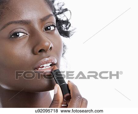 Close-up portrait of young woman applying lipstick over white background View Large Photo Image Stock Photo - Close-up portrait of young woman applying lipstick over white background. Fotosearch