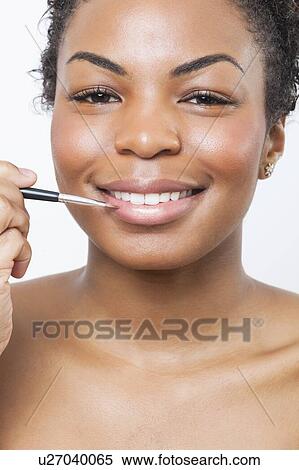 Close-up portrait of young woman applying lip gloss with brush View Large Photo Image Stock Photography - Close-up portrait of young woman applying lip gloss with brush. Fotosearch