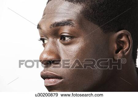Stock Photo - Close-up shot of thoughtful young man looking away against white background. Fotosearch