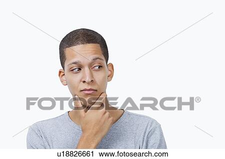 Confused young mixed race man with hand on chin against white background View Large Photo Image Stock Image - Confused young mixed race man with hand on chin against white background. Fotosearch