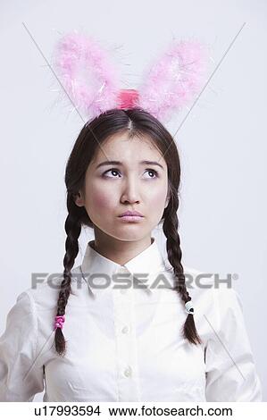 Picture - Contemplative Asian woman with bunny ears against white background. Fotosearch